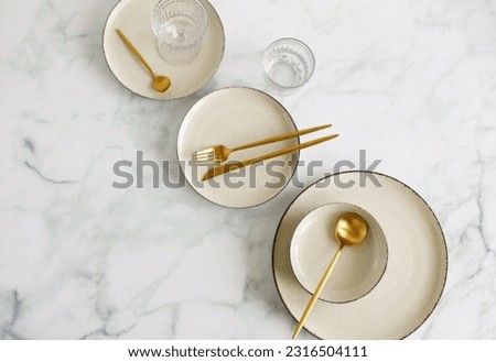 Empty beige ceramic plates and cutlery on marble background top view with copy space . Modern kitchen utensils.Space for text .Business food brand template.