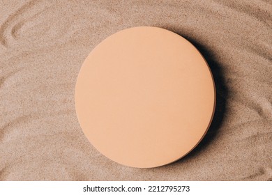 Empty Beige Round Platform Podium For Cosmetics Or Products Presentation On Natural Beige Beach Sand Background. Wavy Curved Ornaments On Sand, Drawn By Hand. Top View