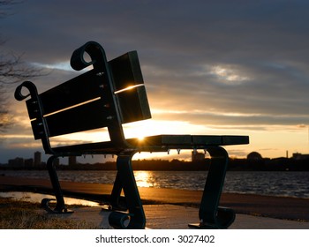 Empty bench backlit against sunset