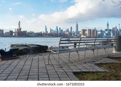 Empty Bench at Bushwick Inlet Park in Williamsburg Brooklyn New York along the East River with a view of the Manhattan Skyline