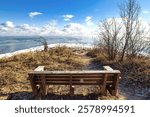 An empty bench faces a cloud shrouded Lake Michigan from a point along the frozen shoreline on a frigid Winter day at Harrington Beach State Park, near Belgium, Wisconsin