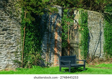 Empty bench in front of a large rusted gate