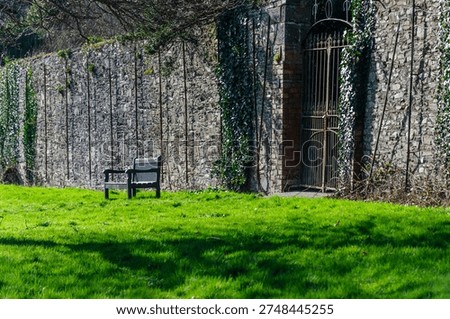 Empty bench in front of a large rusted gate