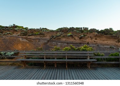 An empty bench in front a rock cliff.