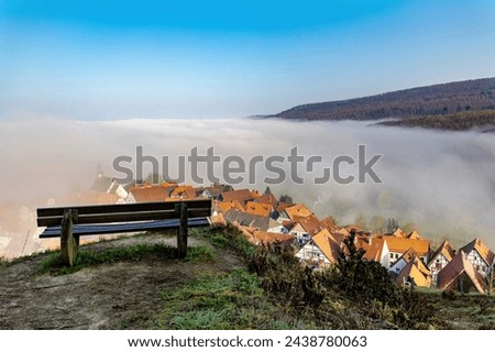 Empty bench on the top of the hill against the background of the city covered with fog, beautiful view near town of Schieder-Schwalenberg in the state of North Rhine-Westphalia in Germany