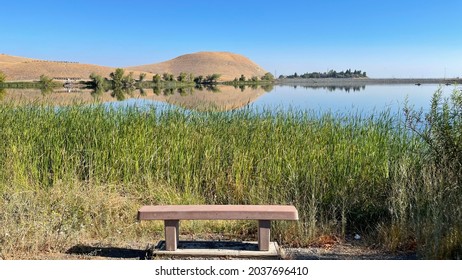 An empty bench over looking a beautiful blue sky and blue lake