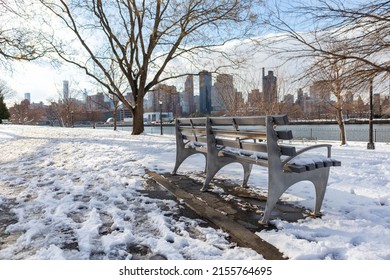 Empty Bench At The Snow Covered Rainey Park In Astoria Queens New York During The Winter Along The East River