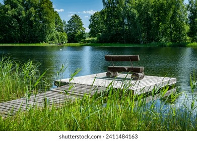 Empty bench at wood pier pontoon on lake. Wooden footbridges, swampy lake shore. Lake Bilska, Latvia. - Powered by Shutterstock