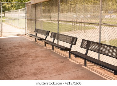 Empty benches in a little league baseball dugout with chain link fence