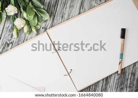 Empty big note book on wooden desk flowers and pen with text "I love you more every day". Concept wedding album for wishes