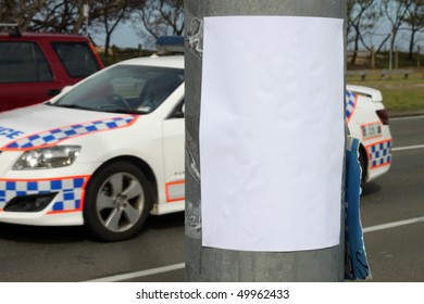 Empty Bill Poster On Light Pole With Police Squad Car In The Background.