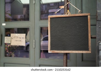 Empty black board hangs on an street's coffee shop. Street. Market. Copy space. Urban. Sale. Trading. Outdoor. Business - Powered by Shutterstock