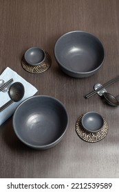 An Empty Black Bowl Complete With A Sake Glass Is Placed On A Black Wooden Table And A Blue Tablecloth