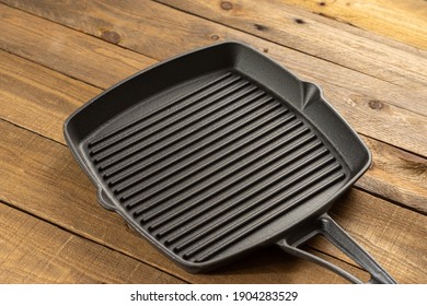 An Empty Black Cast Iron Grill Pan. Wood Background.