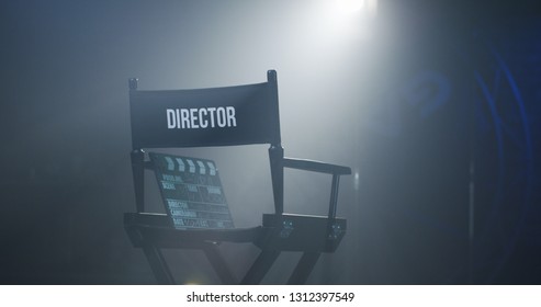 Empty black chair with sign Director and clapperboard in spotlight on filming set