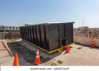 An Empty Black Dumpster Is Seen At A Construction Site By A Boardwalk At The Beach