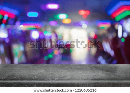 Empty black marble stone table top on abstract blurred game center shop and nightclub lights background - can be used for display or montage your products