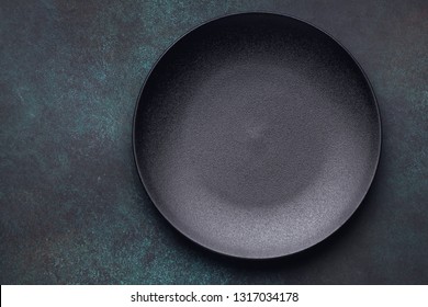 Empty black plate on dark background. Top view, with copy space