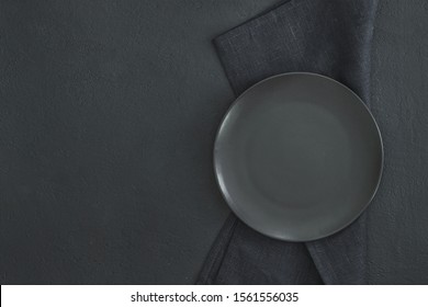Empty Black Slate Plate On Dark Stone Table And Napkin. Food Background For Menu, Recipe. Table Setting. Flatlay, Top View. Mockup For Restaurant Dish