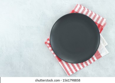 Empty Black Slate Plate On Grey Stone Table And Napkin. Food Background For Menu, Recipe. Table Setting. Flatlay, Top View. Mockup For Restaurant Dish