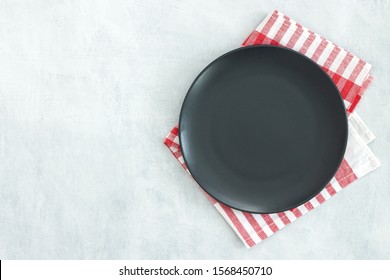 Empty Black Slate Plate On Grey Stone Table And Napkin. Food Background For Menu, Recipe. Table Setting. Flatlay, Top View. Mockup For Restaurant Dish