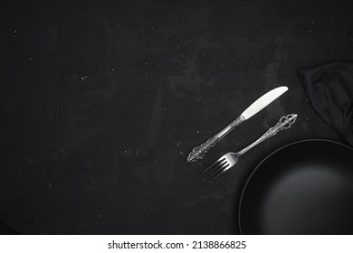 Empty Black Slate Plate On Dark Stone Table. Food Background For Menu, Recipe. Table Setting. Flatlay, Top View. Mockup For Restaurant Dish