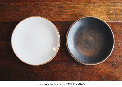 Empty black and white colored crockery two plates on wooden dining table - Powered by Shutterstock