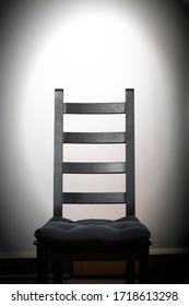 Empty Black Wooden Chair On White Background In Spotlight At Darkness. Prison, Scary, Mystical, Strange, Isolation Concept. Noir, Dark Atmosphere. Waiting For Someone. Vacant Place. House With Ghosts