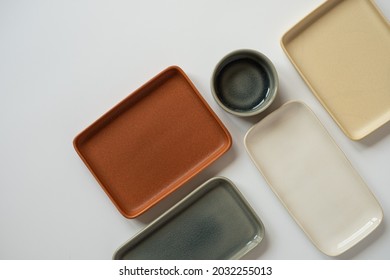 Empty blank ceramic round bowl and square plates on white background. Flat lay, top view of traditional handcrafted homemade kitchenware concept - Shutterstock ID 2032255013
