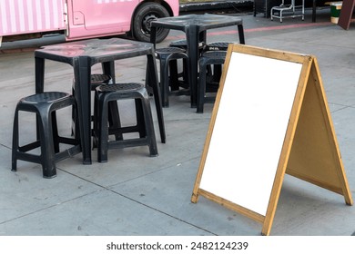 Empty blank for mockup sandwich chalkboard next to tables and chairs and a food truck in a square in Brazil - Powered by Shutterstock