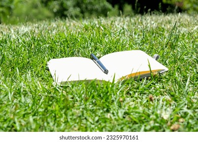 Empty blank notebook with pen on the grass. Take a note everywhere concept photograph.