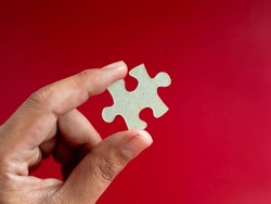 Empty Blank Space Of A Piece Of Puzzle Jigsaw Element In Man's Hand Isolated On Red Background, Minimal Style, Close-up. Business Solution, Solve, Mission, Partnership, Success And Strategy Concepts.