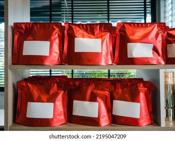 Empty Blank White Label Of Modern Red Coffee Bag Packaging. Mockup Template Sticker Label. Row Of Vivid Foil Paper Zipper Pouch Packaging For Coffee Bean Showing On Wooden Shelf.