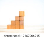 Empty blank wooden cube blocks as growth graph steps with a big one on top, isolated on wood desk on white background. Business growth process, education, success building and organizational concepts.