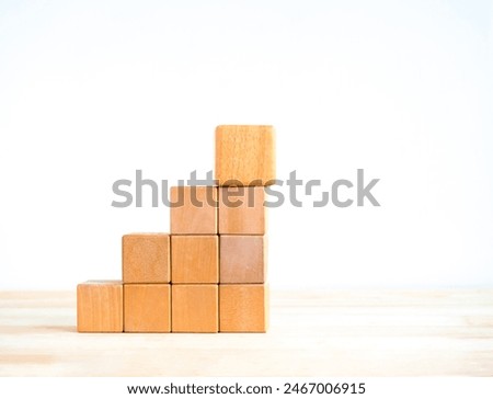 Empty blank wooden cube blocks as growth graph steps with a big one on top, isolated on wood desk on white background. Business growth process, education, success building and organizational concepts.