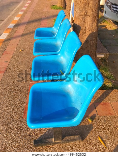 Empty\
blue chair at the public bus stop on the\
footpath.
