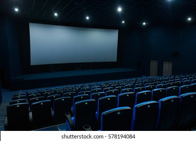 Empty Blue Cinema Room With White Screen And Seats. Side View
