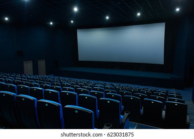 Empty blue cinema with white screen and seats. Side view