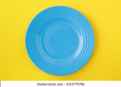 Empty Blue Plate On Yellow. From Above View.