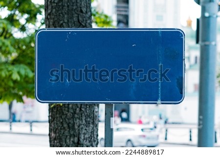 An empty blue rectangular road sign stands on the city's park. Information. Panel. Signpost. Traffic. Roadsign. Rectangular. Urban. Board. Destination. Metal. City. Border. Direction. Help
