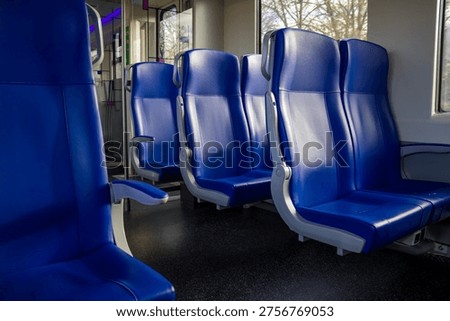 Empty blue train seats in second-class carriage at Deventer station. High quality photo