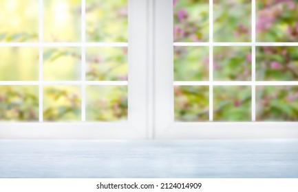 Empty blue wooden desk stands by the window with a view of the blooming spring garden. In the background is a defocus flowering tree with bright pink flowers - Powered by Shutterstock