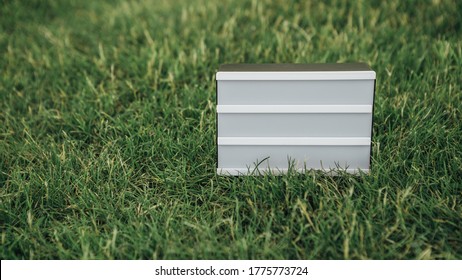 Empty Board For Sign Or Message. Empty Space For Inscription. Close Up Shot Of Advertising Or Sliding Light Box On Saturated Green Lawn Or Grass. Mock Up Image For Your Text.