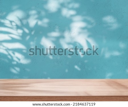 Empty board or table top and blue stucco pattern wall with leaf shadows. Place for your product display. 
