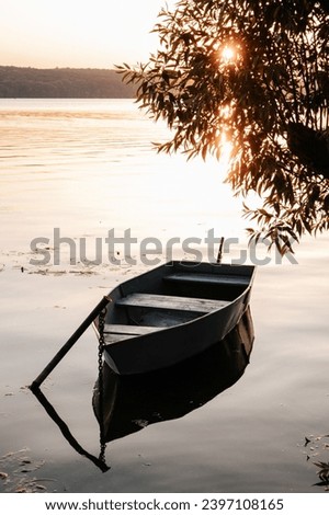 empty boat in the river under a tree at sunset