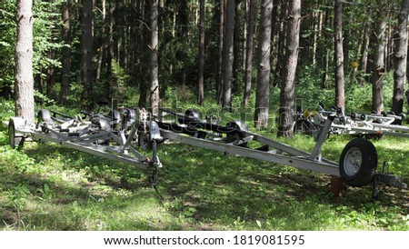Empty boat trailers on forest parking at Sunny summer day, watercrafts transport storage