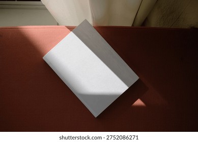 empty book mockup on soft blue chair, shadow overlay, hard light. For advertising, brand design, stationery presentation