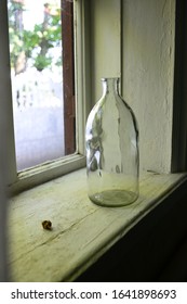 An empty bottle stands on a windowsill in a village house