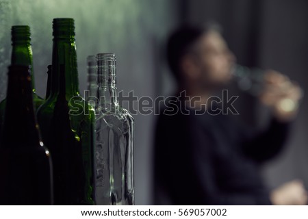 Empty bottles of alcohol with drinking man