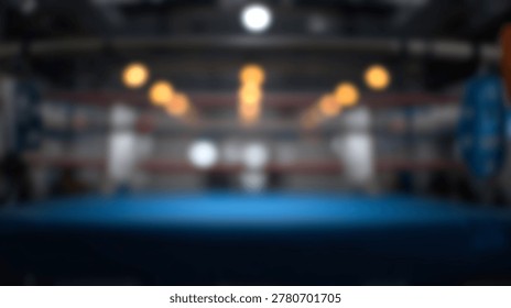 An empty boxing ring with a blue mat and ropes is illuminated by overhead lights in a sports arena.